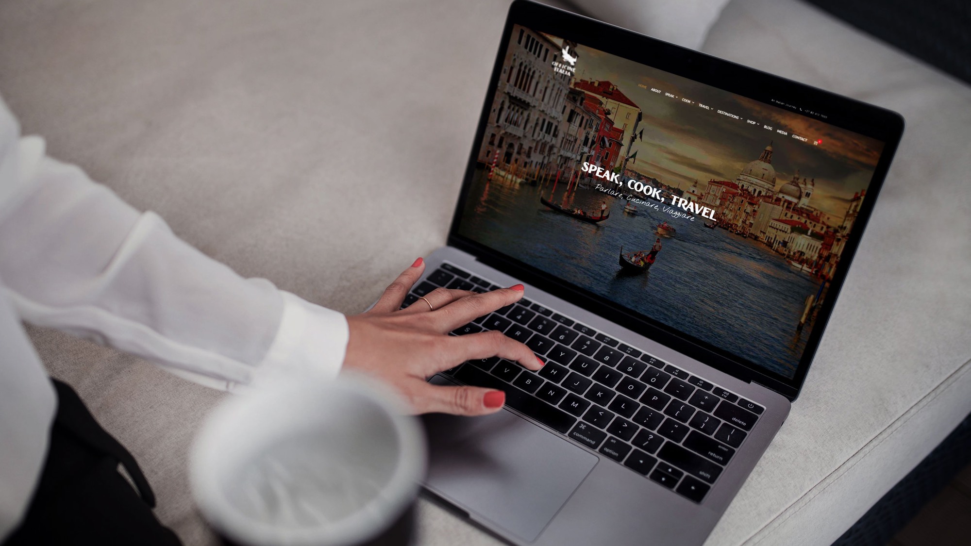 The Officine Italia homepage open on a laptop, the Grand Canal behind the words Speak, Cook, Travel.