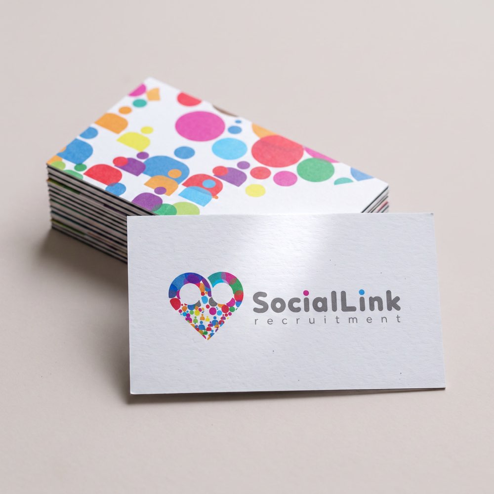 A stack of Social Link business cards, the scattered-dot reverse showing and the heart mark on the card in front.