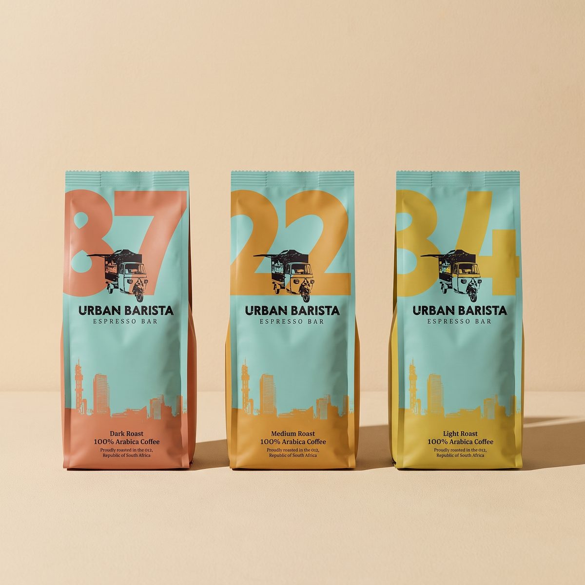 Three Urban Barista coffee bags in duck-egg teal, each carrying a large number in coral, ochre or mustard.